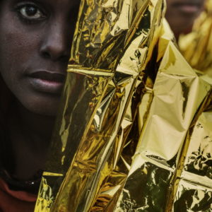 Mediterranean Sea, Italy. A young woman wrapped in a thermal blanket after being rescued by sailors of the Italian Coast Guard.