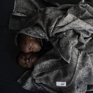 Mediterranean Sea, Italy. A grieving mother hugs her daughter while wrapped in a woollen blanket , aboard the ship "Ubaldo Diciotti" of the Italian Coast Guard.